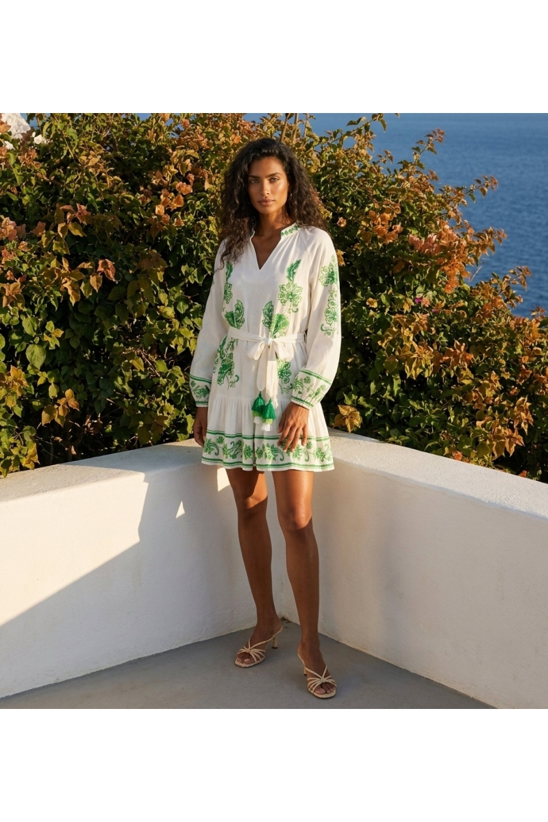 Vestido corto blanco manga larga con bordado floral verde, escote en V, cintura anudada con borlas y falda escalonada.