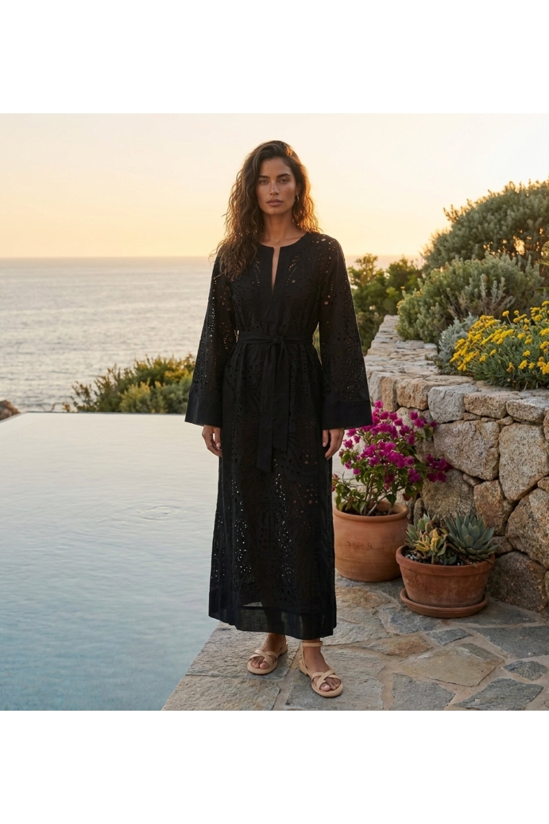 Elegant long black dress, flowing fabric, styled by an infinity pool with a stunning sunset and boulders.