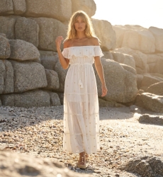Vestido maxi rosa hombros descubiertos, falda escalonada, bordado floral y borlas, tejido ligero y transparente.