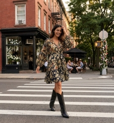Navy blue floral short-sleeve V-neck dress with tiered skirt and tie waist, sheer fabric, styled outdoors at a cafe.