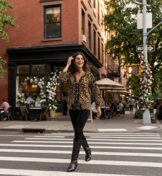 Blusa negra suelta con estampado de leopardo dorado y blanco, cuello con volantes, pompones y borlas, estilo urbano.