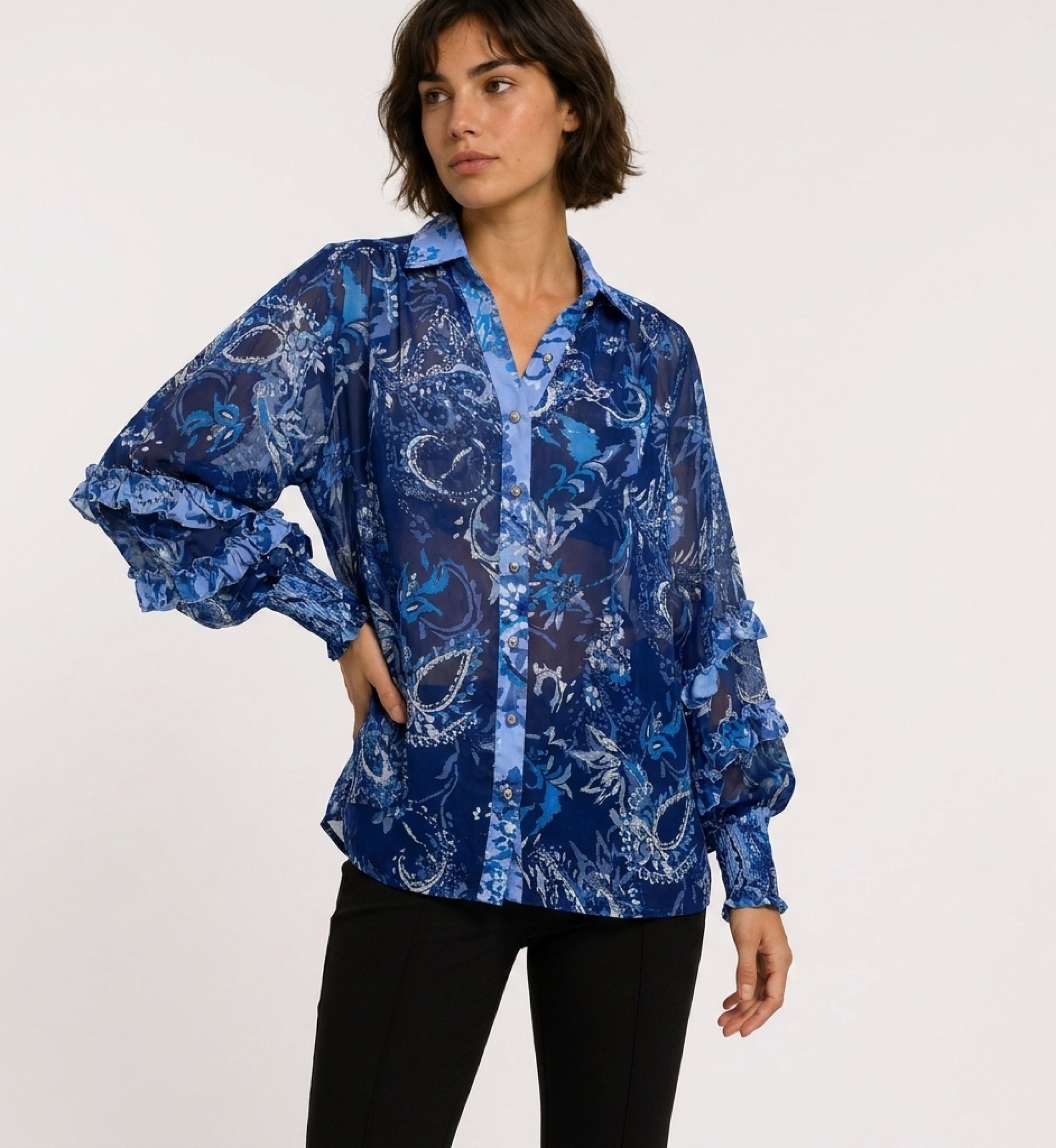 Vue trois-quarts d'une blouse transparente bleue à manches longues, motif cachemire floral, poignets volantés, col V.