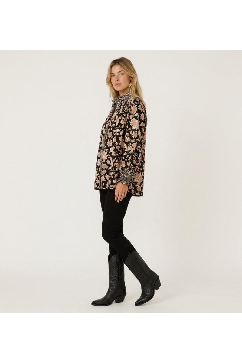 Blusa negra manga larga, estampado floral crema y óxido, cuello, puños con volantes, tejido ligero.