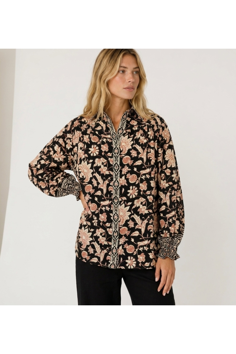 Black long-sleeve floral blouse with cream and rust pattern, collared neckline, and ruffled cuffs in lightweight fabric.