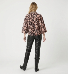 Blusa negra manga larga floral, estampado crema y óxido, cuello, puños con volantes, tela ligera, vista trasera.