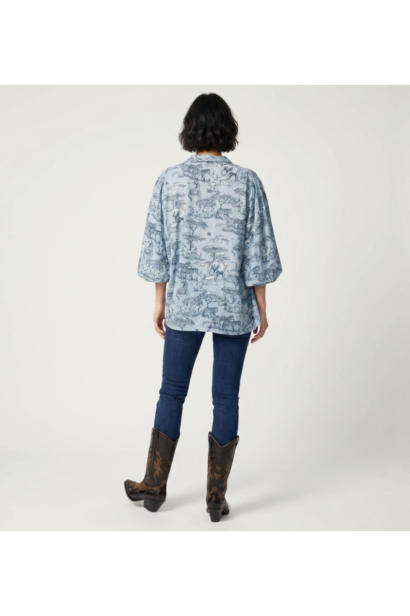 Camisa abotonada azul claro de manga larga, vista trasera. Estampado animales safari azul/blanco, mangas abullonadas fruncidas.