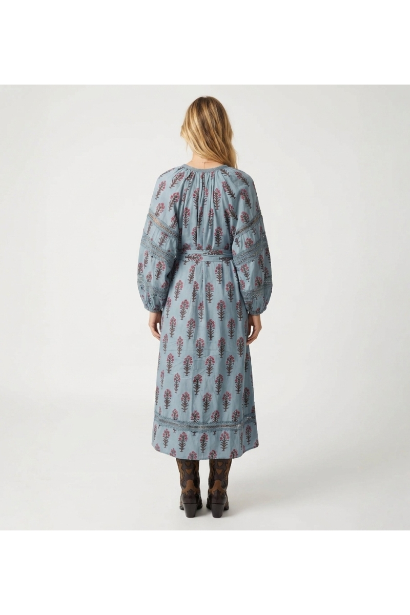 Robe midi bleu clair à motifs floraux rouges et marron, manches longues bouffantes, taille nouée avec pompons, vue de dos.