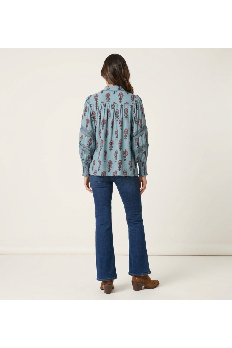 Chemisier bleu clair à fleurs, vue dos. Motif floral rose et marron, manches ballon avec dentelle, poignets smockés.