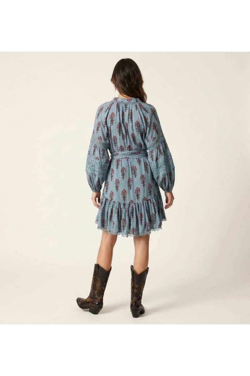Robe courte fleurie bleu clair, vue dos. Motifs floraux rouges et marron, manches ballon dentelle, col, taille nouée.
