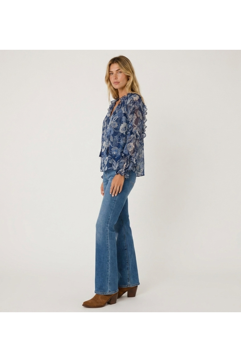 Blusa azul transparente de manga larga con estampado floral, volantes en hombros y puños, cuello con cordón, vista tres cuartos.