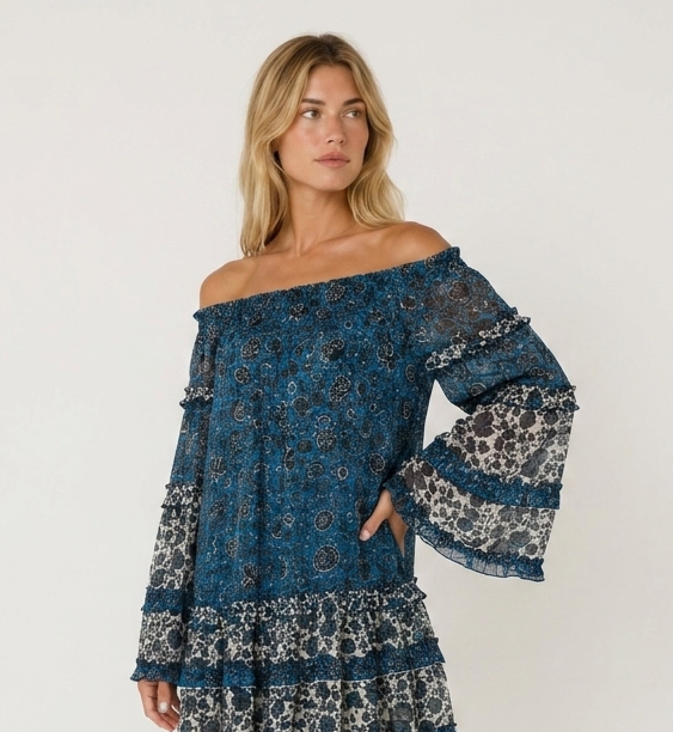 Mini robe bleue et blanche épaules dénudées, manches longues, volants étagés, tissu transparent à fleurs.
