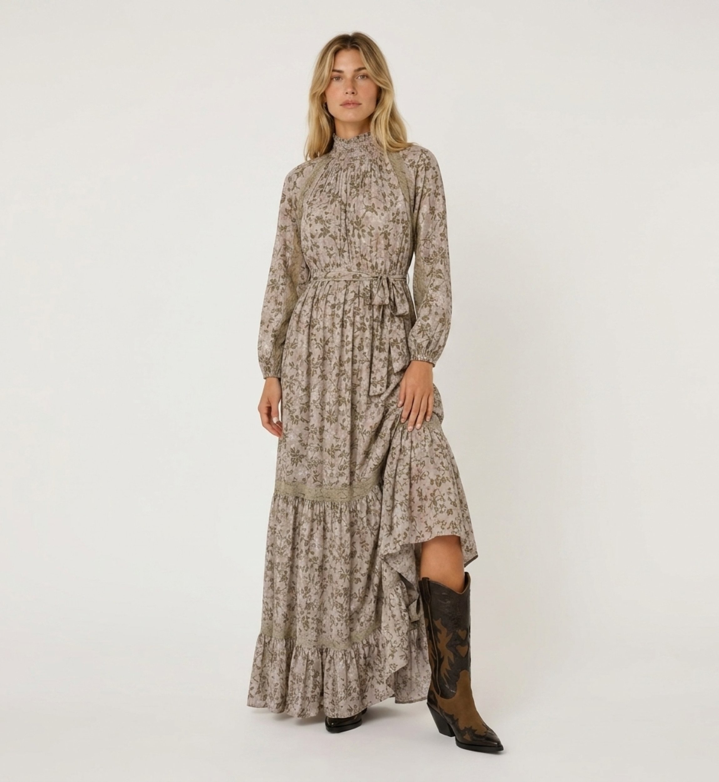 Robe longue maxi rose pâle à motifs floraux verts et dorés, col smocké, manches bouffantes, détails en dentelle.