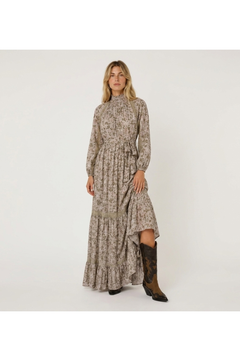 Robe longue maxi rose pâle à motifs floraux verts et dorés, col smocké, manches bouffantes, détails en dentelle.