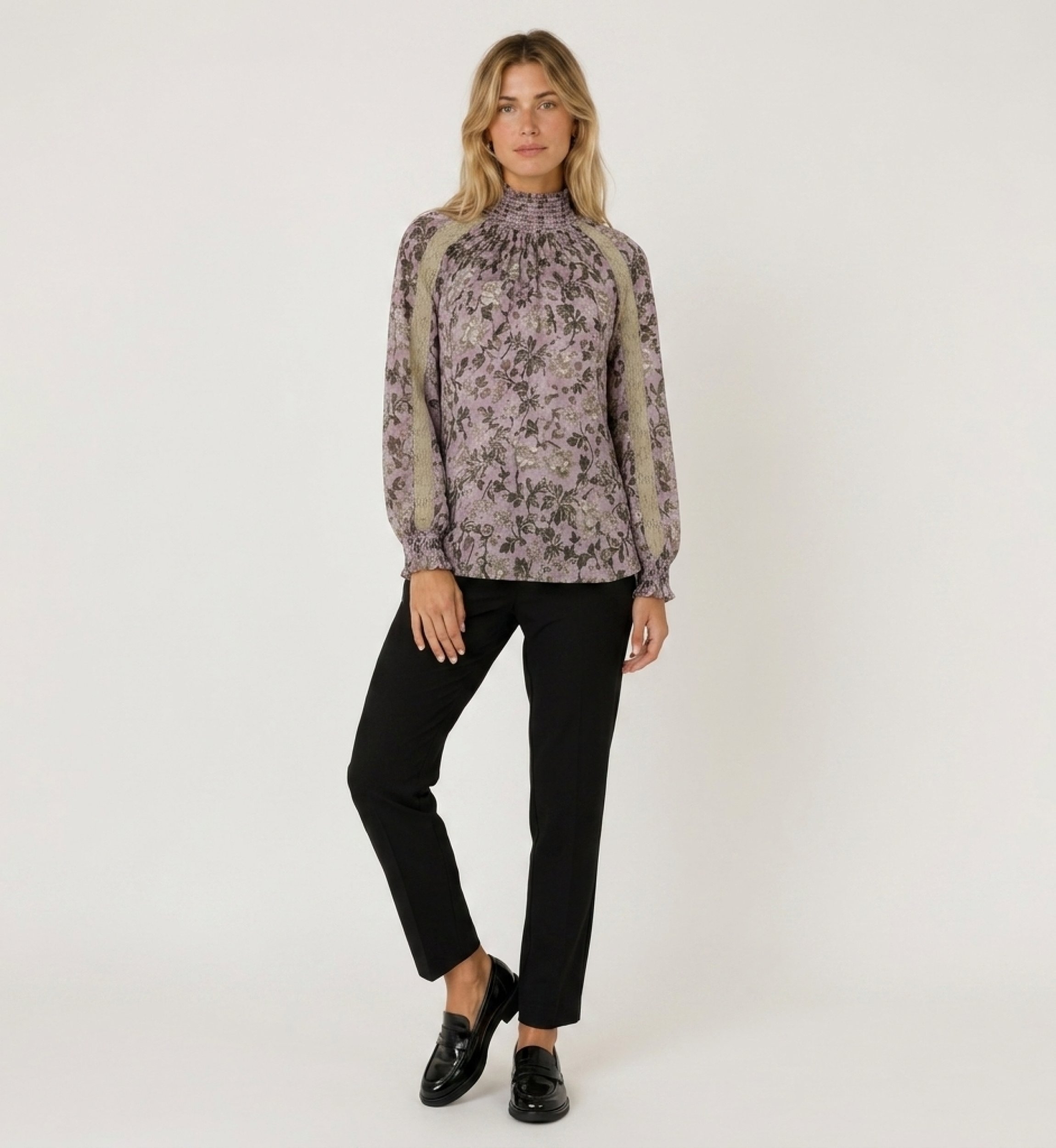 Blusa morada de manga larga y cuello alto con estampado floral oscuro, ribete de encaje beige y puños fruncidos, vista frontal.