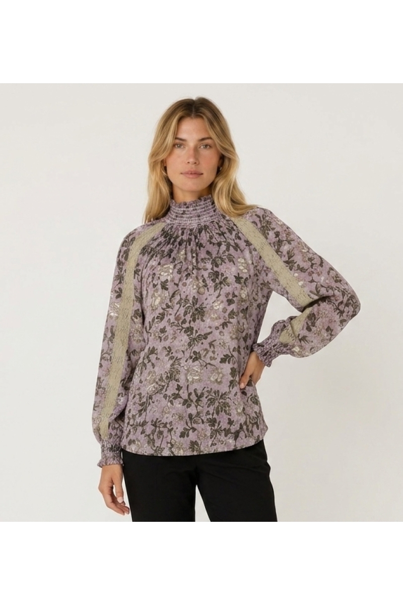 Blouse violette manches longues col montant à motif floral sombre, dentelle beige et poignets smockés, vue de trois-quarts.