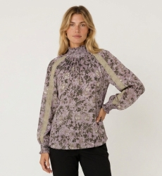 Blouse violette manches longues col montant à motif floral sombre, dentelle beige et poignets smockés, vue de trois-quarts.