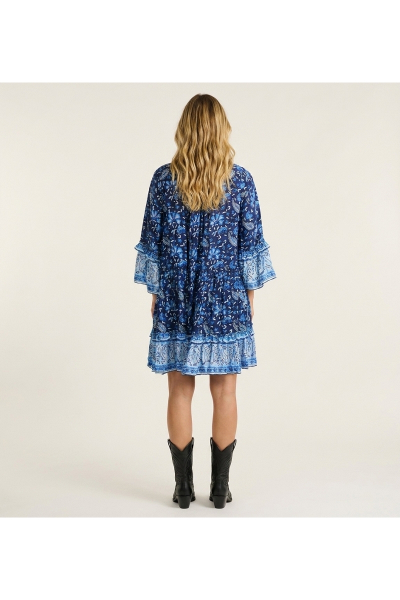 Espalda de mini vestido azul y blanco estampado cachemir floral, cuello V, mangas tres cuartos con volantes, falda escalonada.