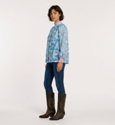 Blue long-sleeve floral blouse with pink and white flowers, high neck, loose fit, cotton-like fabric, three-quarter view.