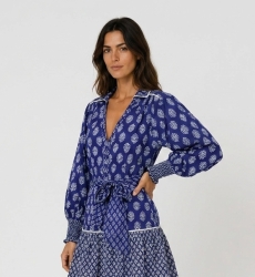 Vista tres cuartos de blusa azul con estampado floral, cuello en V, manga larga y puños smock.