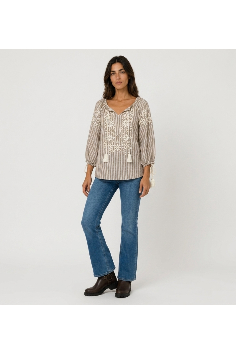 Front view of a brown and white striped peasant blouse with v-neck, 3/4 balloon sleeves, white floral embroidery, and tassels.