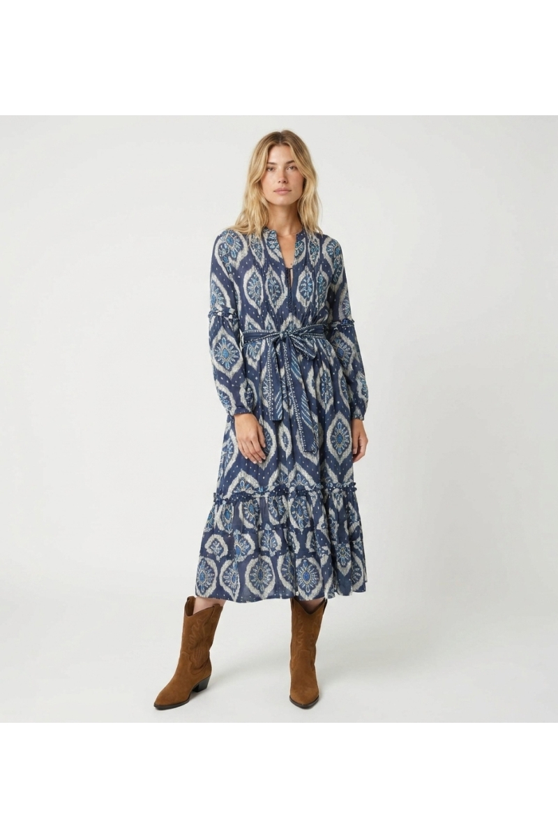 Robe midi bleue et blanche motif ikat, manches longues bouffantes, jupe à volants, ceinture à nouer.