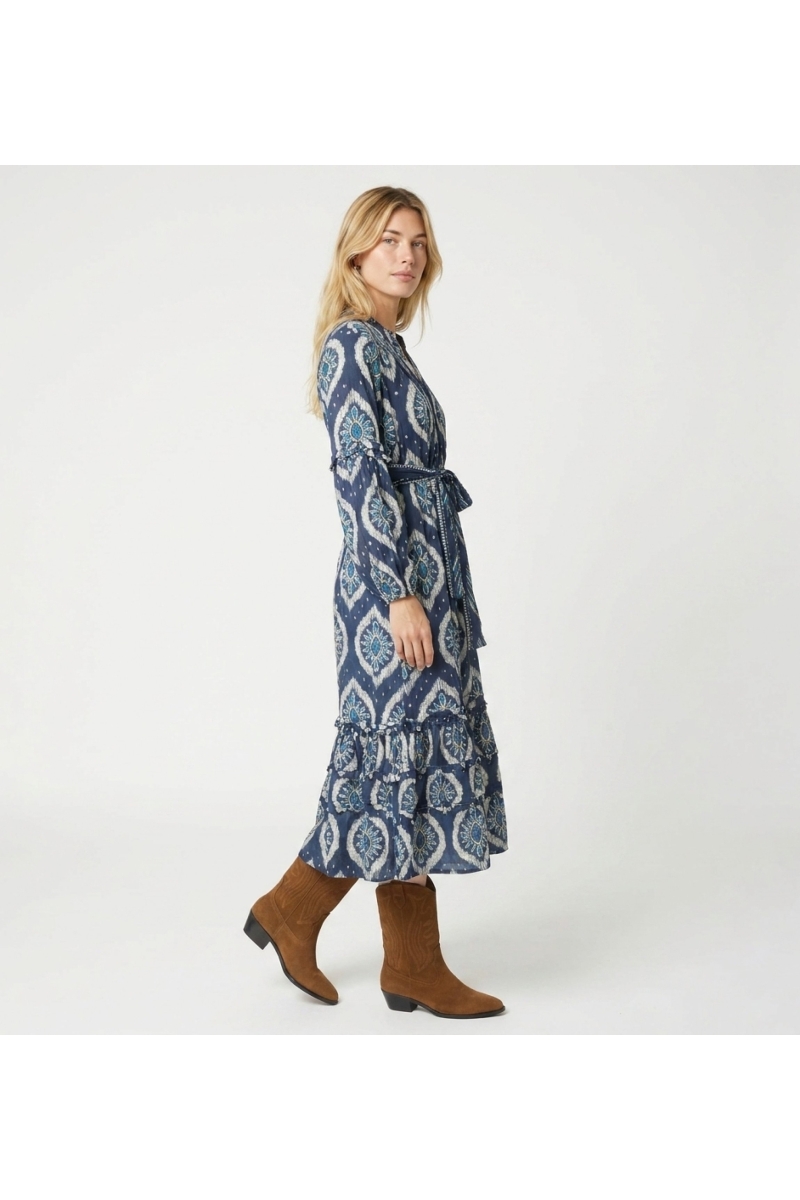 Robe midi bleue et blanche motif ikat, manches longues bouffantes, jupe étagée, ceinture à nouer, vue trois-quarts.