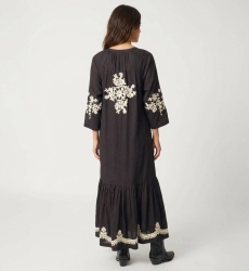 Black midi peasant dress, loose fit with gold floral embroidery on back, sleeves & hem. Tie-waist, rear view.