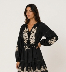 Robe courte noire ample, manches longues ballon, jupe à volants, broderie florale blanche, taille nouée.