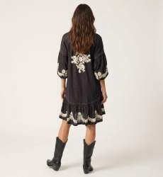 Robe courte noire ample, manches ballon longues, jupe à volants, broderie florale blanche, taille nouée, vue dos.