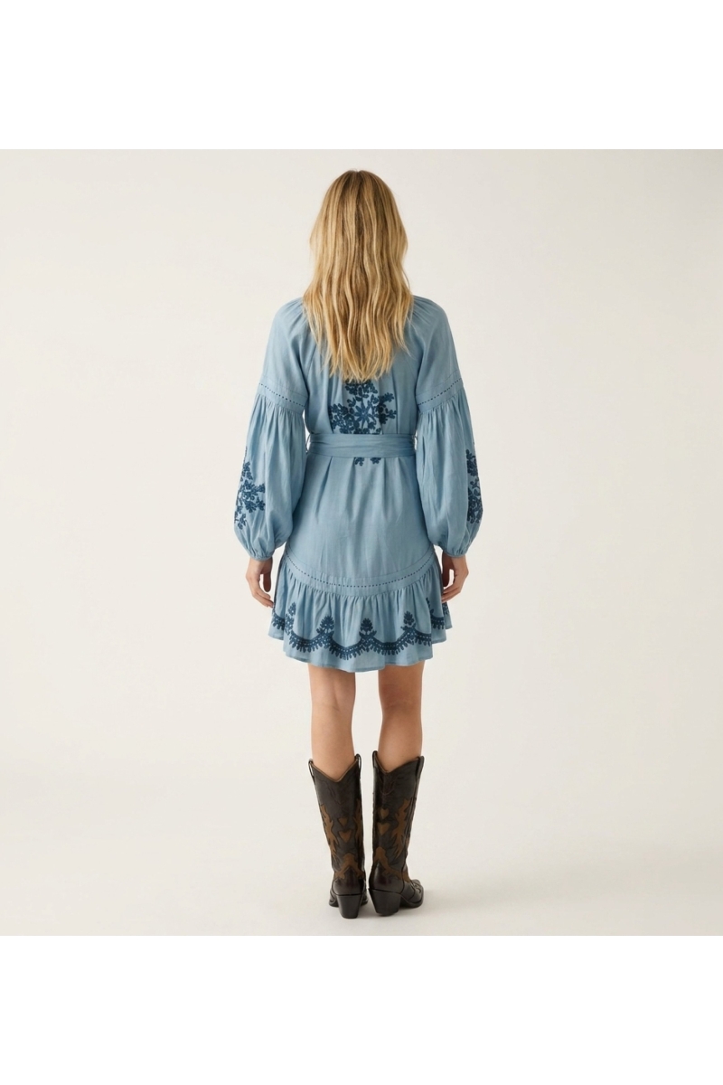 Black mini dress, loose fit, long balloon sleeves, tiered skirt with white floral embroidery, tie-waist, back view.