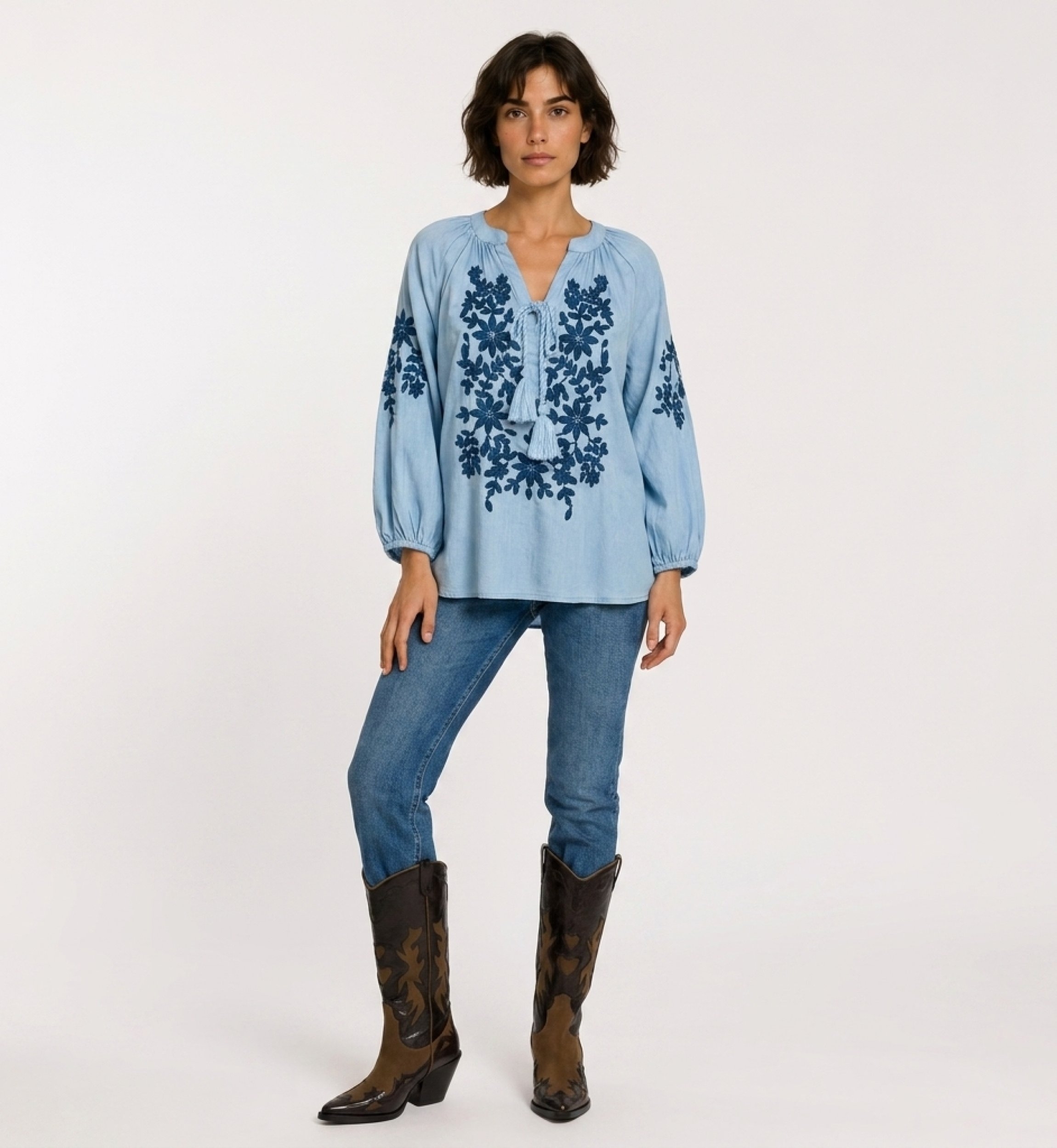 Blouse paysanne noire à manches longues, col V avec lien, broderie florale crème sur le devant. Tissu aspect lin, vue de face.