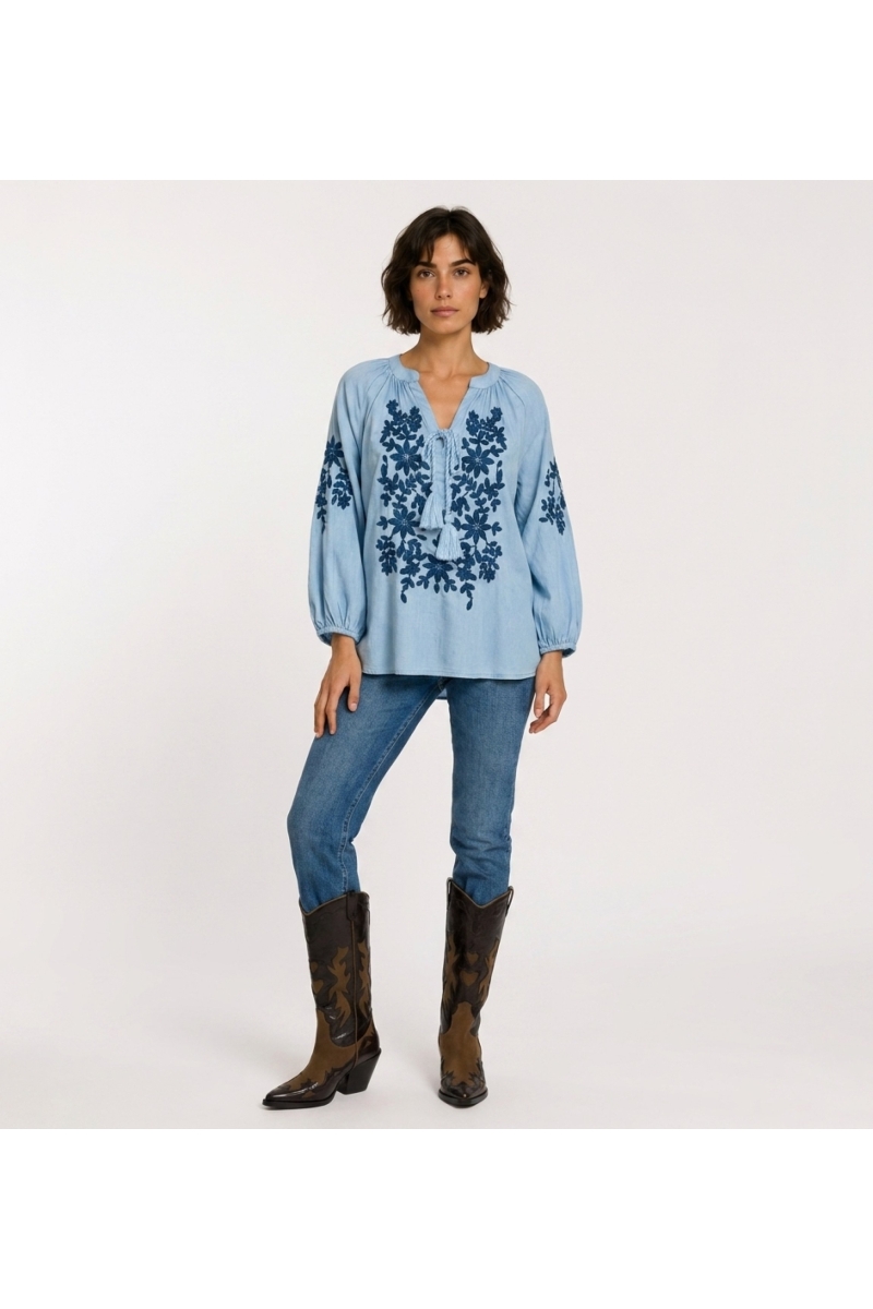 Blouse paysanne noire à manches longues, col V avec lien, broderie florale crème sur le devant. Tissu aspect lin, vue de face.