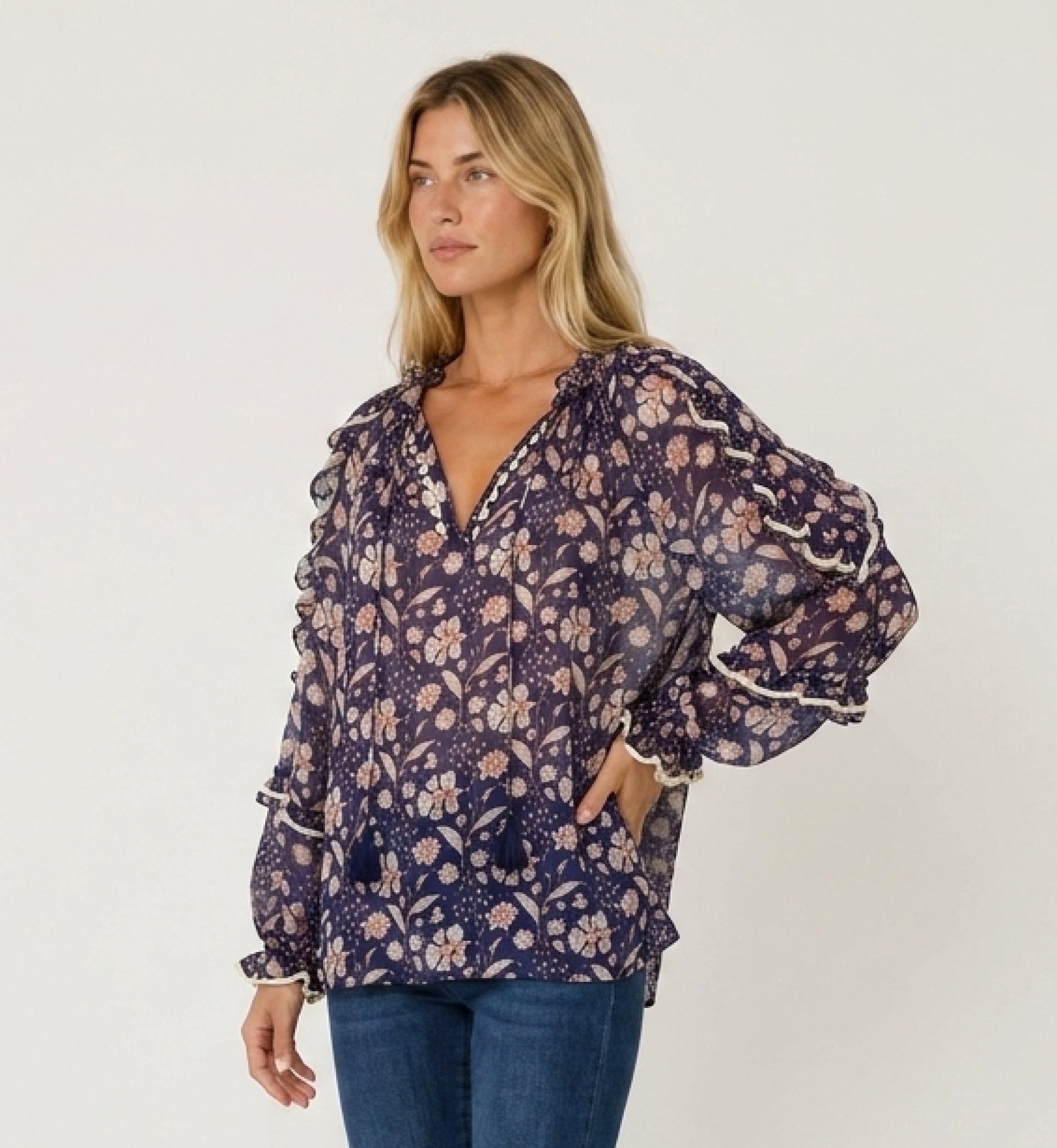 Sheer navy blue floral blouse with white and peach print, ruffled long sleeves, V-neck with ties, loose fit, three-quarter view.
