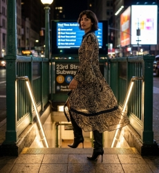 Longue robe maxi noire et beige à motifs, col chemise, boutonnée, manches cloche, taille coulissée, vue urbaine nuit.