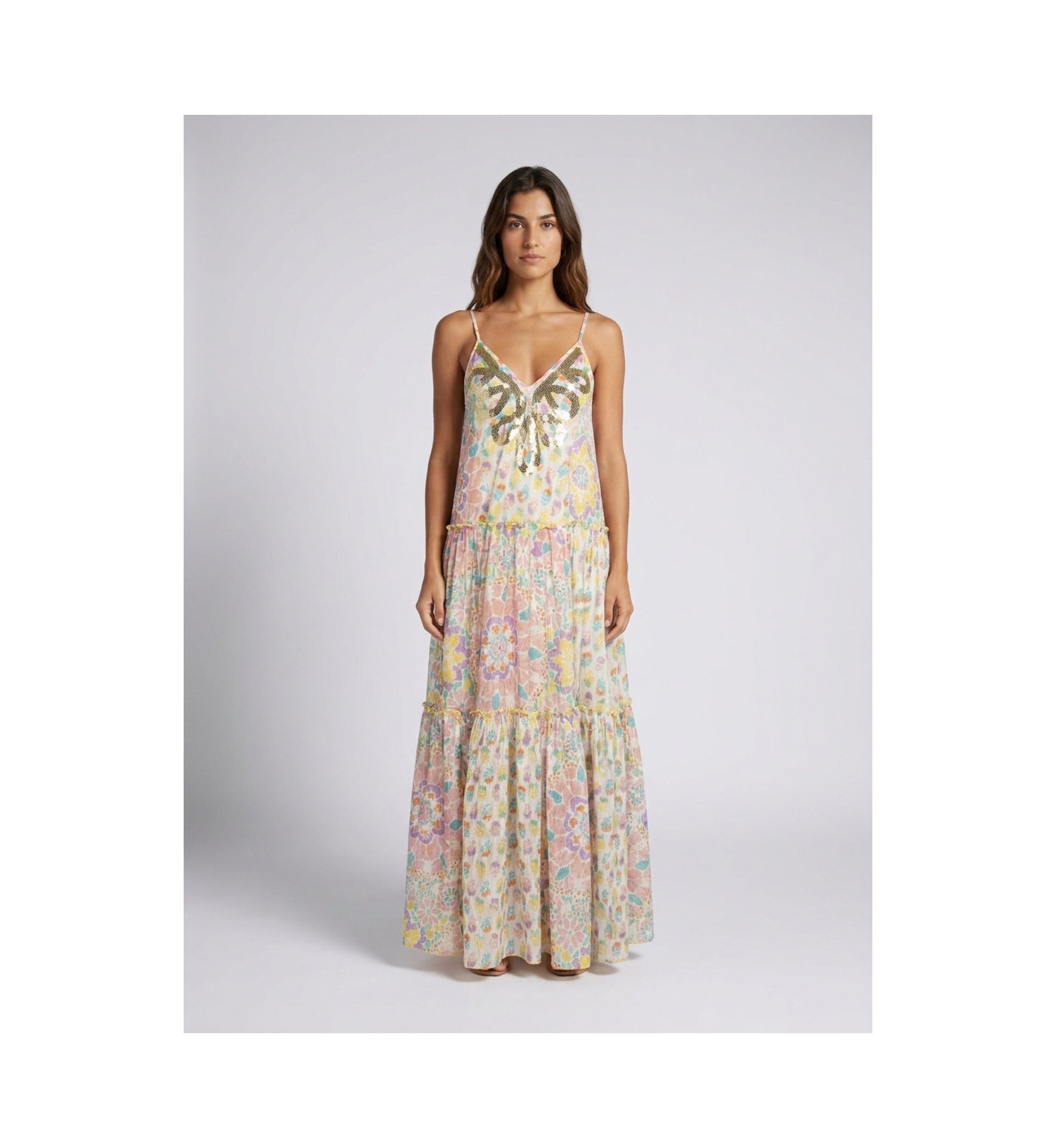 Robe longue blanche à volants, fines bretelles, décolleté en V fleuri multicolore. Encolure ornée de sequins.