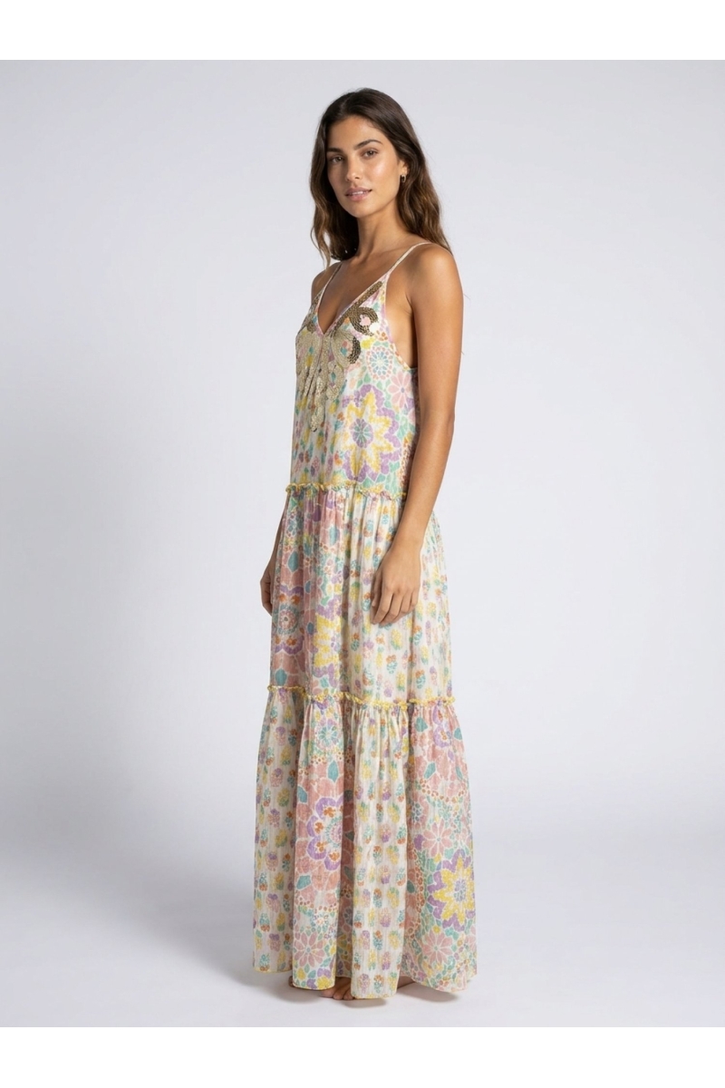 White long tiered maxi dress, thin straps, V-neck with gold/silver sequins, vibrant floral pattern, model side view.