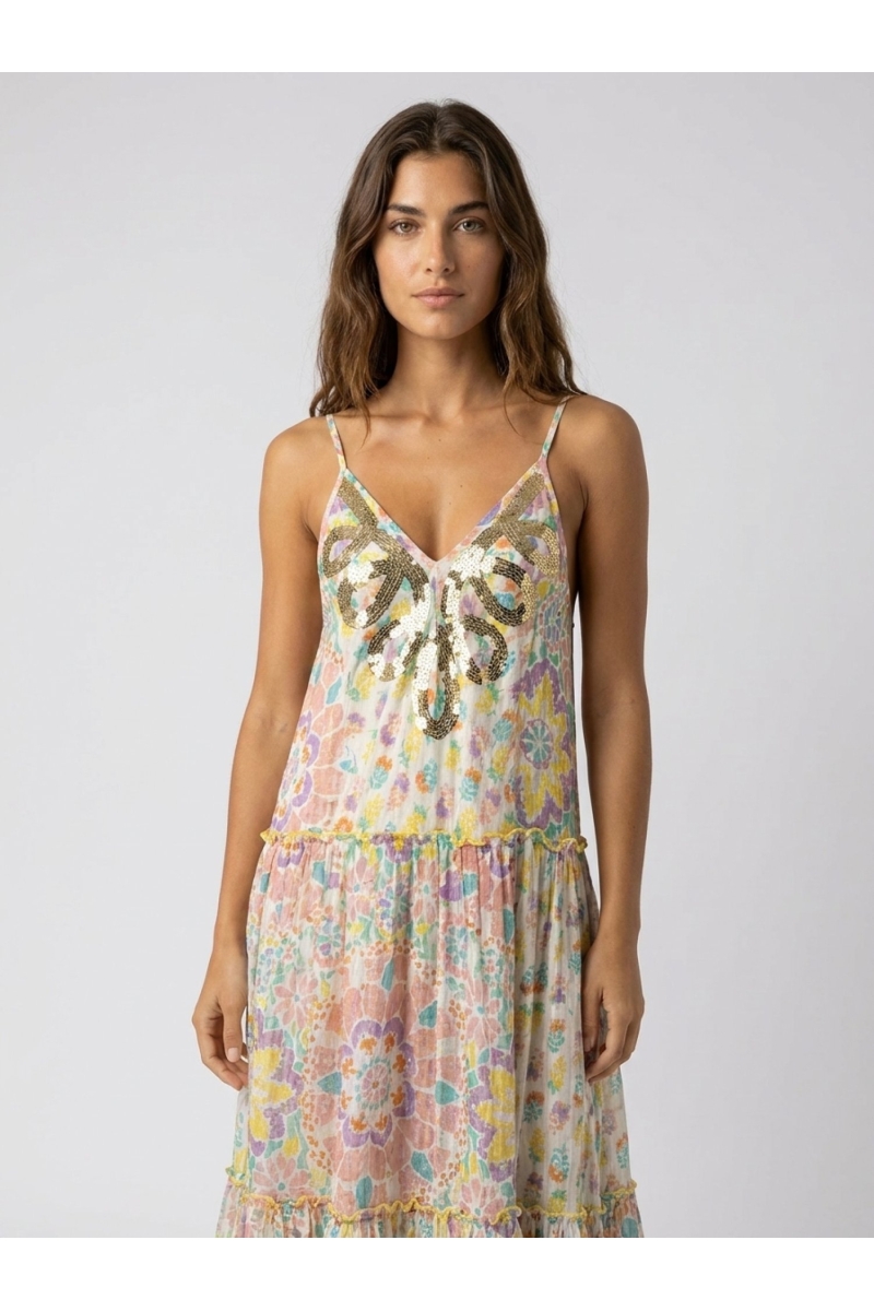 White tiered maxi dress with thin straps, sequined V-neckline, and vibrant multicolored floral print.